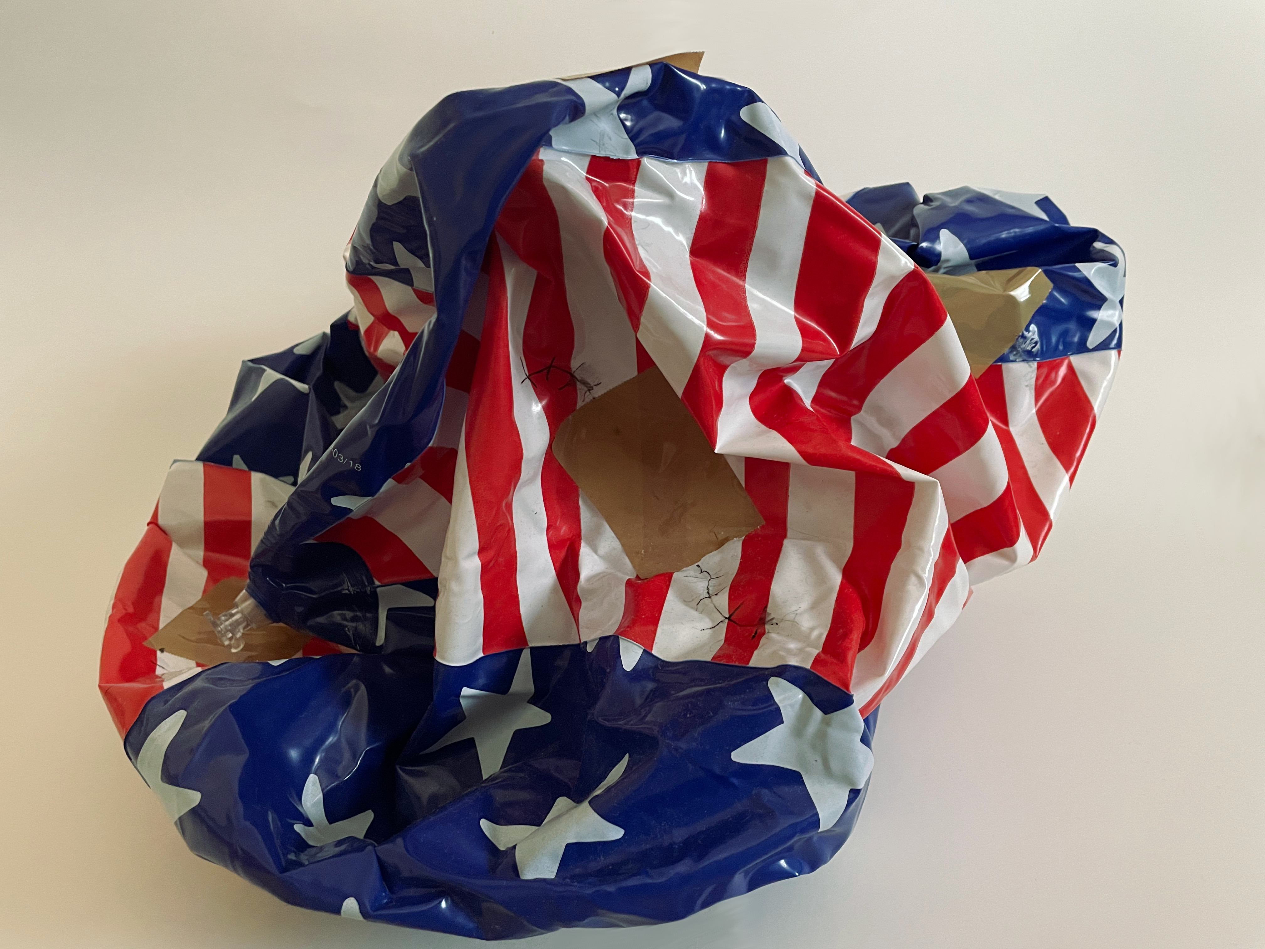 
                              photo of a American flag Beach ball deflated and crumpled held together by tape and stitched up