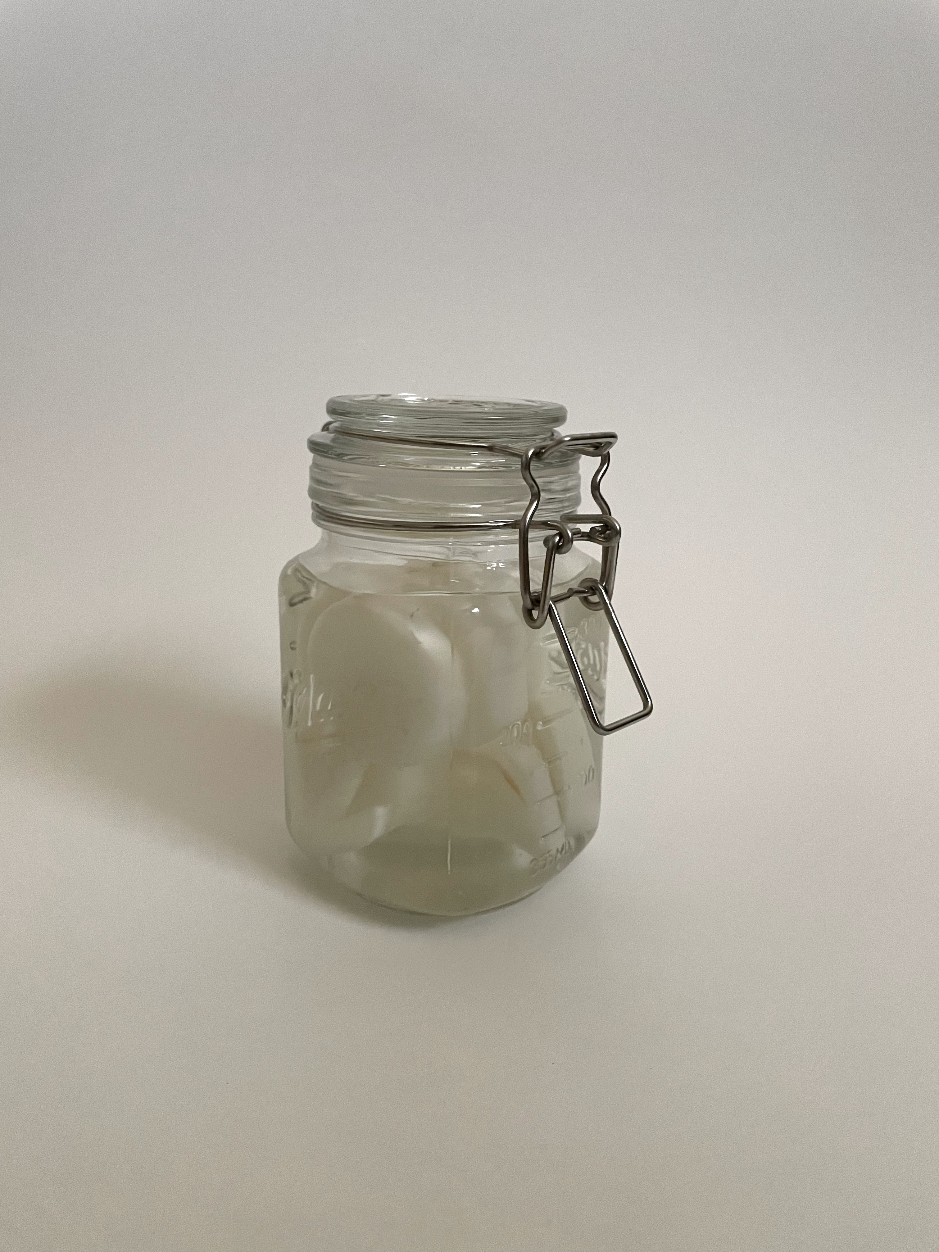 a glass jar with pickled daikon radishes in the shape of the male sign